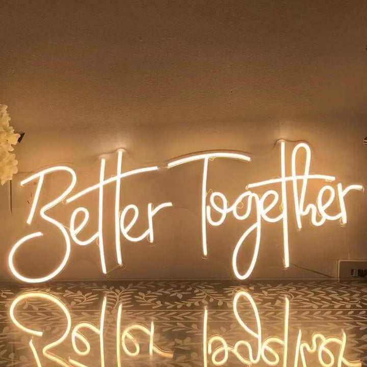 A warm white "Better Together" LED neon sign placed on the shelf. 