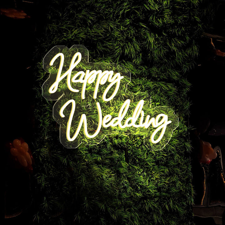 The Happy wedding neon sign from ManhattanNeons.com looks amazing among the leaves in the dark.