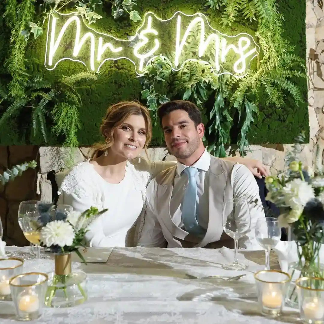 a cute couple sits in front of our Mr & Mrs wedding neon sign from ManhattanNeons.com.